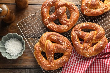 Tasty pretzels with salt on wooden table, flat lay