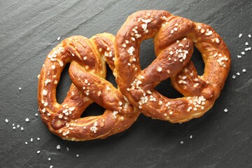 Tasty pretzels with salt on black table, flat lay