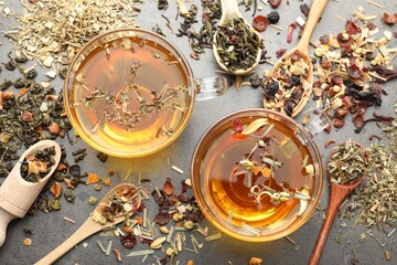 Aromatic herbal tea and dry leaves on grey table, flat lay