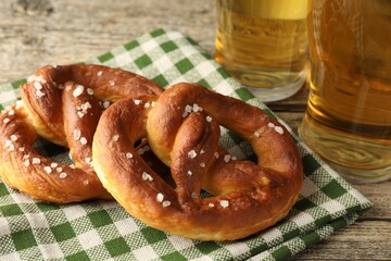 Tasty pretzels and glasses of beer on wooden table, closeup