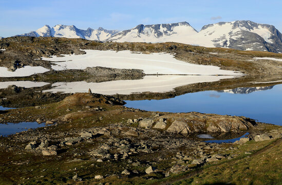 Landscape photo with a view of snow-capped mountains and the mirror lake Fantesteinsvatnet early in the morning on the Sognefjell Road near Løm in Norway