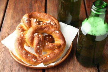 Tasty pretzels and bottles of beer on wooden table, closeup