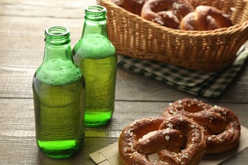 Tasty pretzels and bottles of beer on wooden table, closeup