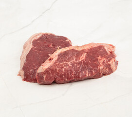 Two fresh raw beef steaks displayed on a white marble surface – High Resolution Raw Meat Image...