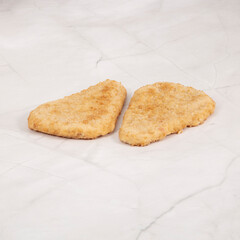 Two crispy chicken cutlets resting on a clean marble surface – High Resolution Raw Meat Image for Food Industry or Food Packaging
