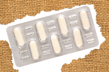 Medical pills in blister packaging on jute cloth, close-up, top view.