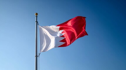 Fototapeta premium Flag of Bahrain waving proudly against a clear blue sky in a serene outdoor setting