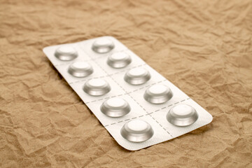 Medical pills in blister packaging on kraft paper, close-up.