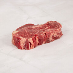 Raw ribeye steak fresh cut displayed on white marble background – High Resolution Raw Meat Image for Food Industry or Food Packaging