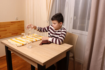 Naklejka premium Boy wipes glasses and cups with a towel. Housework.