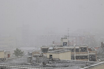 A snowy cityscape with a few buildings in the background