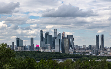 Fototapeta premium A stunning view of a modern city skyline with sleek skyscrapers rising against a moody sky filled with fluffy clouds, reflecting contemporary urban architecture and design in Moscow, Russia