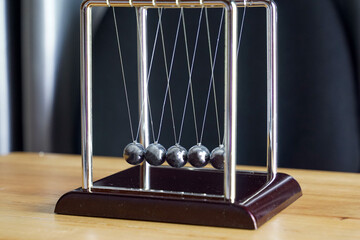 The Newton's cradle is a device that demonstrates the conservation of momentum and the conservation of energy with swinging spheres. Soft and selective focus.