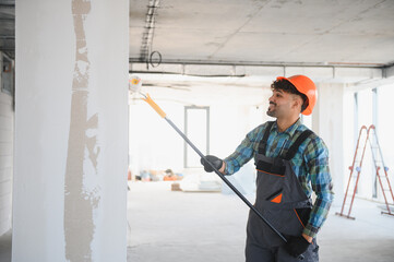 Smiling arab construction worker painting wall with roller brush