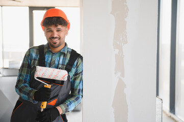 Painter holding paint roller smiling during renovation work