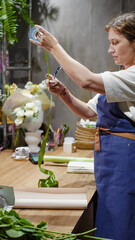 A female florist measures ribbon for decoration. Small business.  Owner. Close-Up
