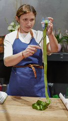 the florist works. A female florist measures ribbon for decoration. Small business.  Owner. Close-Up
