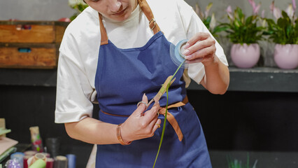 the florist works. A female florist measures ribbon for decoration. Small business.  Owner. Close-Up