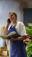 The florist is talking on the phone, smiling, and writing down business notes in a notebook. Small business. Close-Up.