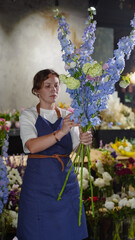 A florist in a flower shop makes a bouquet of blue delphiniums. Small business.  Close-Up.  Soft focus.