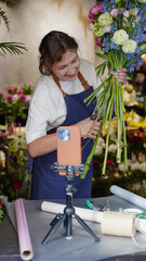 Florist conducts online training on creating bouquets using a phone. Florist records instructional...