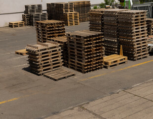 In a spacious warehouse setting, there is a large collection of wooden pallets that have been...