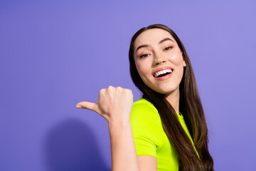 Fototapeta premium Smiling young woman in a vibrant outfit giving a thumb gesture against a purple background, expressing positivity and style