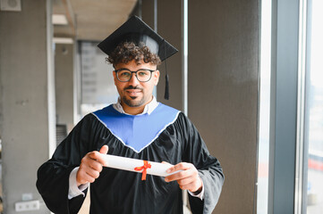 Happy arab student showing his university diploma at graduation ceremony
