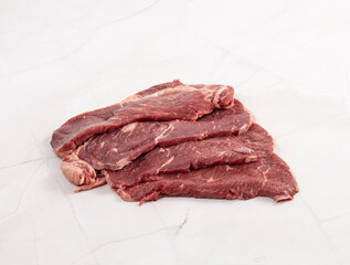 Fresh raw beef flank steak slices on a white marble background – High Resolution Raw Meat Image for Food Industry or Food Packaging