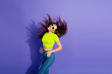 Young stylish woman in vivid fashion posing against a vibrant purple backdrop in dynamic motion for...
