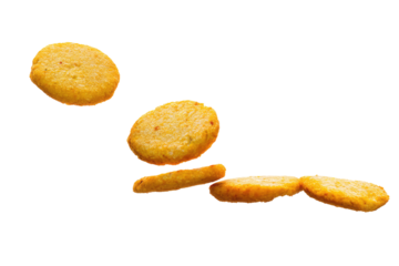 A still life shot of several golden brown hash browns scattered on a black background in a studio setting on transparent background