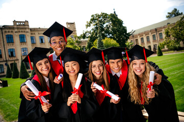 Group of happy young graduates celebrating college success outdoors in summer day