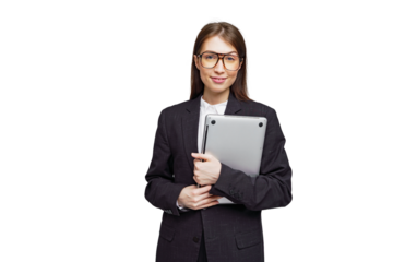 Professional woman in a stylish suit holding a laptop with a confident smile in a modern setting