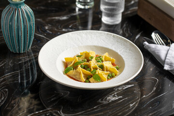 Portion of italian ravioli fagottini dumplings dish with sauce and basil