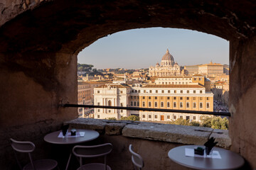 A stunning view of St. Peters Basilica and the Tiber River framed by the brick arch of Castel SantAngelo, capturing the beauty of Rome’s historic skyline in warm morning light