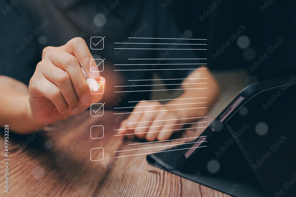 Poster hand checking off tasks on a digital checklist with tablet on wooden table background