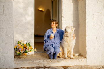A serene moment shared between a woman in blue linen and her loyal white dog, enjoying a peaceful...