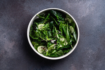 Vegan meal,  green salad with fresh leaf vegetables and herbs (spinach, arugula, cucumber, scallion, parsley)
