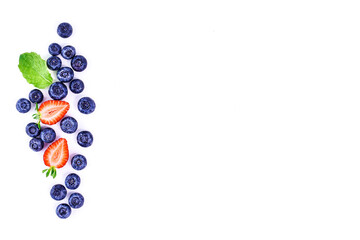 Fresh blueberries and sliced strawberries with mint leaves on a white background. Healthy summer fruits arranged on the side with copy space. Minimalist food composition for design or advertising.