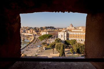 A stunning view of St. Peters Basilica and the Tiber River framed by the brick arch of Castel SantAngelo, capturing the beauty of Rome’s historic skyline in warm morning light