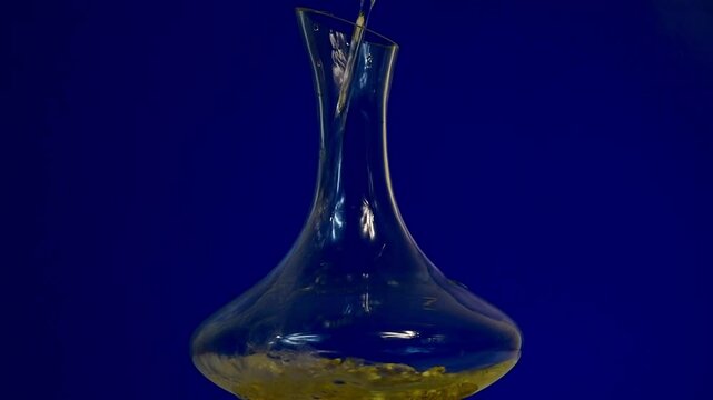 Decantador de vino con flores de manzanilla dentro, con fondo azul y agua cayendo