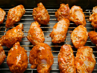Cooking fresh chicken wings on an oven. The product is covered in red Asian style sauce and ready for cooking in high temperature. Party finger snack food.