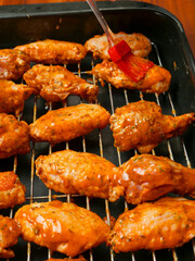 Cooking fresh chicken wings on an oven. The product is covered in red Asian style sauce and ready for cooking in high temperature. Party finger snack food.