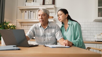 Grandmother comforting and supporting grandfather while looking at laptop show successful project and getting promotion. Happy senior businessman receive good news and talking to his wife. Myrmidon.