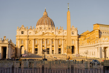 Obraz premium St Peters Basilica and the Vatican obelisk glow in the soft golden hour light in Rome. Ideal for editorial content and travel campaigns highlighting iconic European landmarks