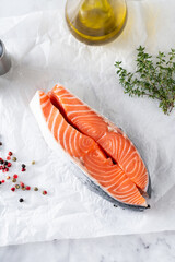 pieces of fresh raw salmon steak on the table with thyme and olive oil. recipe preparation
