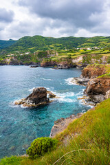 Beautiful bay with rocks on ocean coast with green cliffs at Ponta Delgada, Flores island, Azores, Portugal