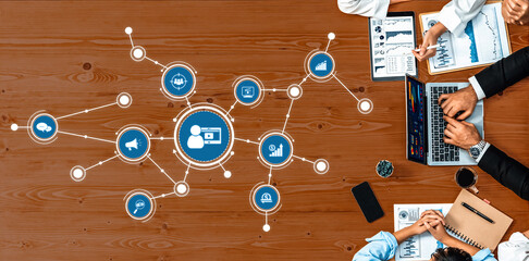 A collaborative marketing strategy session featuring diverse professionals analyzing data and utilizing digital tools on a wooden table, fostering teamwork and innovation. Amity