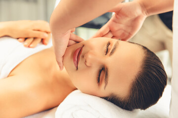 Fototapeta premium Closeup woman enjoying relaxing anti-stress head massage and pampering facial beauty skin recreation leisure in dayspa modern light ambient at luxury resort or hotel spa salon. Quiescent