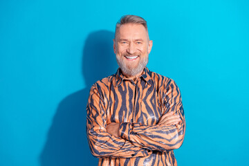 Glamorous Positive Charismatic Elderly Man in a Funky Tiger Print Shirt Against a Blue Background